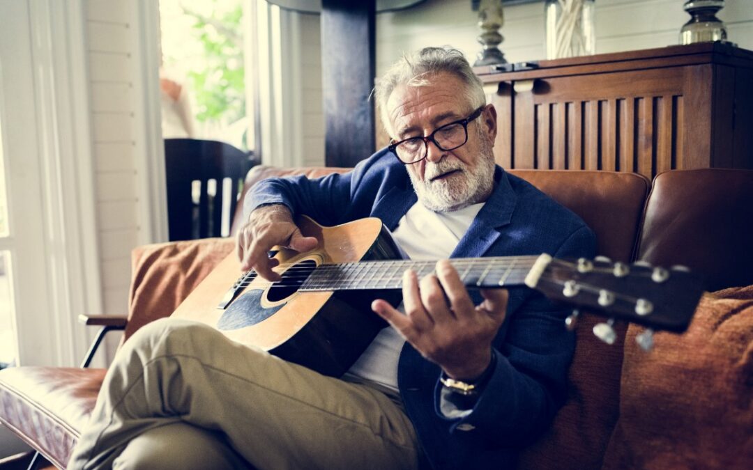 An elderly man is playing guitar